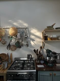 a stove top oven sitting inside of a kitchen next to a wall mounted pot rack