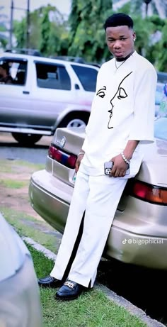 a man sitting on the trunk of a car in front of some parked cars,