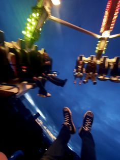 the person is standing on top of a ferris wheel at night time with their feet in the air