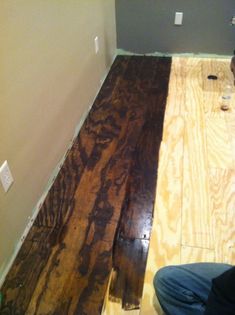 a man laying on the floor in front of a wall with some wood planks