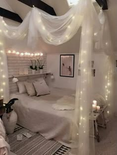 a white bedroom with lights strung from the ceiling and bed canopy over it's headboard