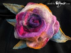 a close up of a flower made out of wool and felt yarns on a black background