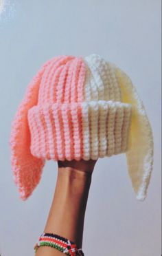 a woman's hand holding up a knitted hat