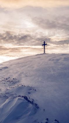 a cross on top of a hill covered in snow