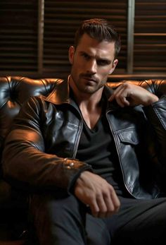 a man sitting on top of a brown couch wearing a black shirt and leather jacket