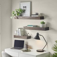 a laptop computer sitting on top of a white desk next to a potted plant