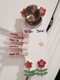 a door hanger that has clothes pins attached to it with flowers and words written on them