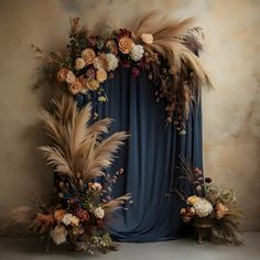 an arrangement of flowers and feathers is displayed on a stage with a blue curtain in the background