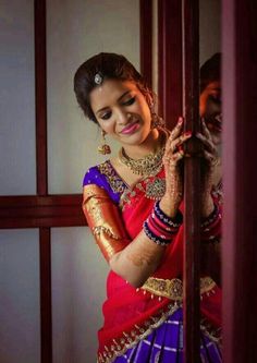 a woman in a red and blue sari is holding her hands on the wall