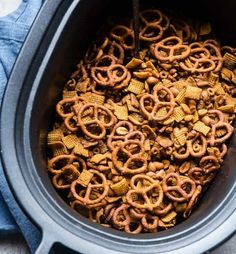 a slow cooker filled with cheetos and pretzels for snacking