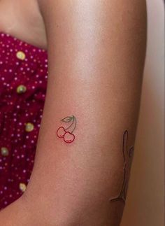 a woman's arm with a tattoo on it that has cherries on it