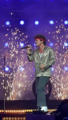 a man standing on top of a stage holding a microphone in front of firework