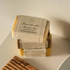 three soap bars stacked on top of each other next to a wooden block and bowl