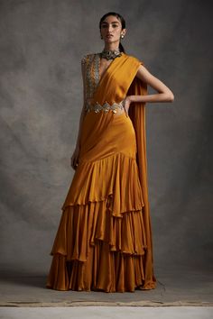 A vibrant pre-stitched layered saree with an embroidered cutwork belt. The saree is paired with a pearl, sequins, tilla & mirror work hand embroidered blouse. The sleeves have pearl & sikka... Luxury Pre-draped Saree With Mirror Work For Diwali, Luxury Traditional Wedding Dress With Drape, Luxury Bollywood Pre-draped Yellow Saree, Luxury Yellow Bollywood Pre-draped Saree, Luxury Bollywood Yellow Pre-draped Saree, Luxury Traditional Saree With Latkans, Drape Lehenga, Bhumika Sharma, Drape Saree