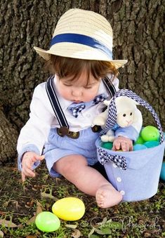 a small child sitting in the grass with an easter basket