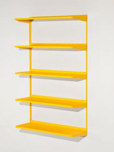 a yellow shelf on the wall with three different shelves in front of it and one is empty