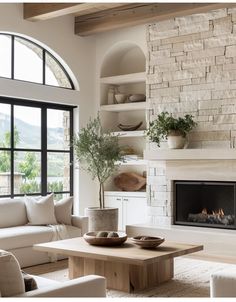 a living room filled with furniture and a fire place in front of a large window