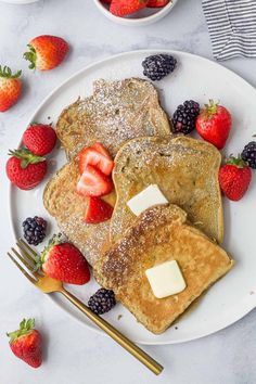 pancakes with butter and strawberries on a white plate