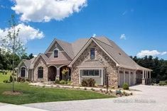 a large brick house with lots of windows on the front and side of it, surrounded by lush green grass