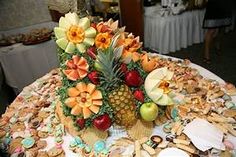 a pineapple surrounded by flowers and fruit on top of a table with other food