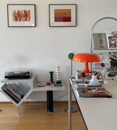 a room with two pictures on the wall and an orange lamp in front of it