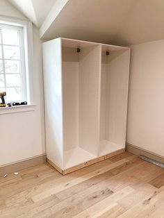 an empty room with white walls and wooden flooring in the foreground, there is a window on the far wall