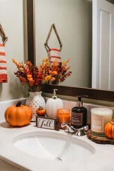 a bathroom sink with candles, pumpkins and other items on it in front of a mirror