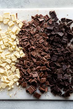 two different types of chocolate on a white cutting board with one being chopped up and the other is uncooked