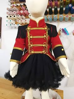 a mannequin dressed in a red and black outfit with gold trims on it