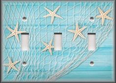 three light switch covers with starfishs in the net on a blue wood background