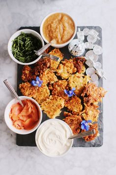 an overhead view of fried food and dipping sauces on a slate platter with silverware