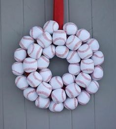 a wreath made out of baseballs is hanging on the front door with a red ribbon