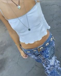 a woman in high waisted jeans and a white top is posing for the camera