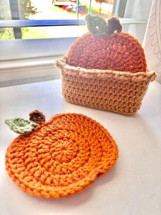 two crocheted baskets sitting on top of a white table next to each other