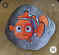 a painted rock with an orange fish on it