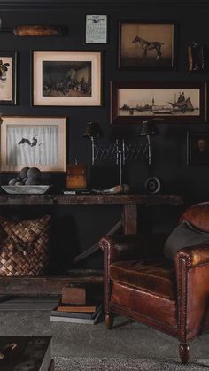 a living room filled with furniture and framed pictures on the wall above an old leather chair