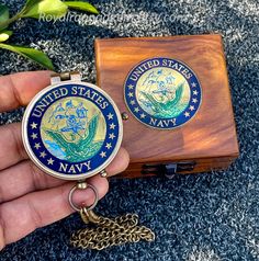 a hand holding a key chain and a wooden box with an image of the united states navy on it