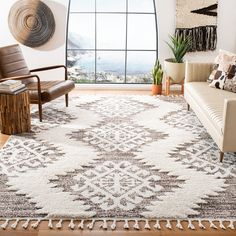 a living room filled with furniture and a large window next to a white rug on top of a hard wood floor