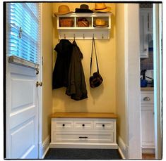 a coat rack with hats and purses hanging from it's sides next to a white door