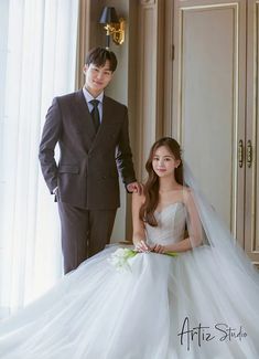 a man in a suit standing next to a woman in a wedding dress