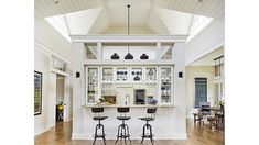 a kitchen with three stools in front of the counter and an open floor plan