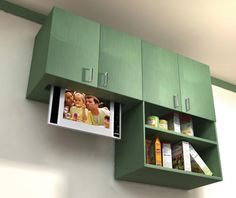 a green cabinet with pictures hanging from it's sides and two shelves on the wall