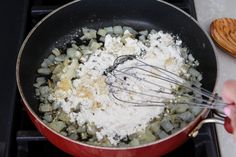 someone is mixing ingredients in a red pan on the stove with a whisk