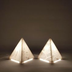 three pyramids with lights on them sitting in the middle of a dark floored room