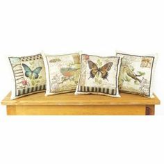 four pillows with butterflies on them sitting on a wooden bench