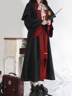 a woman dressed in red and black holding a wand while standing next to a suitcase