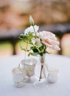 a vase filled with flowers sitting on top of a white table cloth covered tablecloth