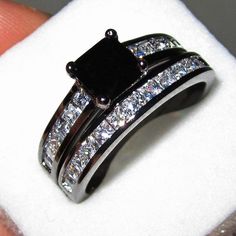 a black and white diamond ring set on top of a napkin in front of someone's finger