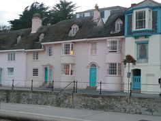 a row of pastel colored houses with blue doors and windows on the top floor