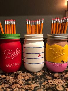 three mason jars with pencils in them sitting on a counter next to each other